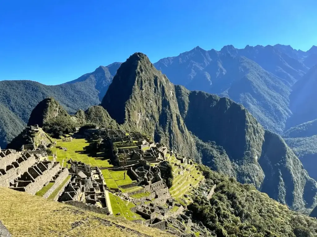 Vista panorâmica das ruínas de Machu Picchu sob céu azul, a cidade perdida dos Incas no Peru - KG Viagens